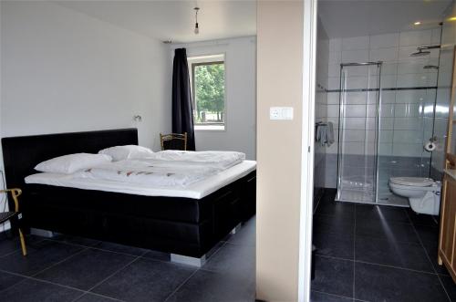 a bedroom with a bed and a shower and a toilet at Bed and breakfast Wouw in Wouw