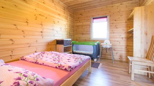a bedroom with a bed and a tv in a wooden cabin at Rodzinne Rusinowo in Rusinowo