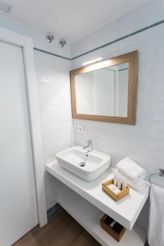 a white bathroom with a sink and a mirror at Casa de la Merced Suites in Málaga