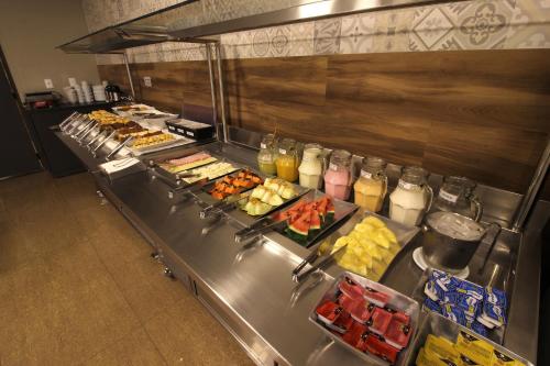 uma linha de buffet com muitos tipos diferentes de alimentos em Impar Suites Barao de Cocais em Barão de Cocais