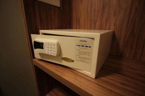 a white microwave sitting on a wooden shelf at Impar Suites Barao de Cocais in Barão de Cocais