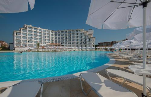 a hotel with a swimming pool with chairs and an umbrella at Sunrise Blue Magic Resort - All Inclusive in Obzor