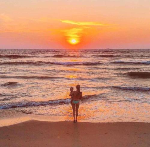 a woman walking on the beach at sunset at Mbeach Nest in Panadura