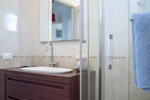 a bathroom with a sink and a glass shower at Fellini - Family Flat in Rimini