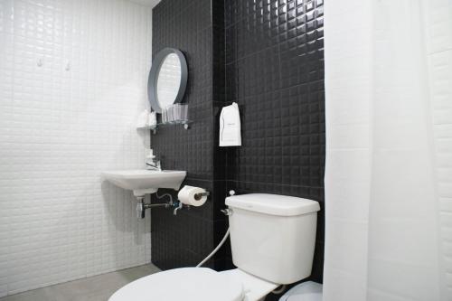 a bathroom with a toilet and a sink and a mirror at Neveu Premier Residence : Ratchada in Bangkok