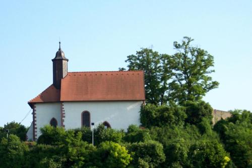 a small white church on a hill with trees at Hotel Riegeler Hof in Riegel