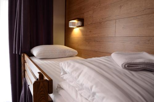 a bedroom with two beds with white sheets and a wooden wall at Music Hostel in Poltava