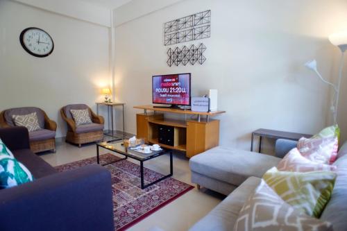 a living room with a couch and a tv at Neveu Premier Residence : Ratchada in Bangkok