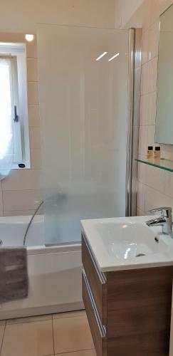 a white bathroom with a sink and a shower at Roggia Apartments by Quokka 360 - central flats with parking space in Lugano
