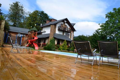 a house with a playground and chairs on a wooden floor at Hata Hutsula in Mykulychyn