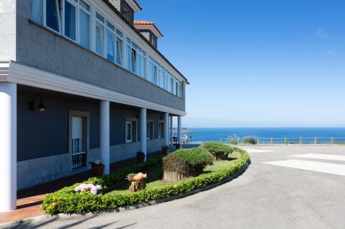 a building with bushes and flowers next to the ocean at Casa Maravilla in Faro de Peñas