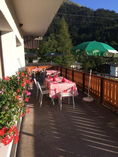 - un balcon avec des tables, des chaises et un parasol dans l'établissement Chalet-Hôtel du Borderan, à La Clusaz