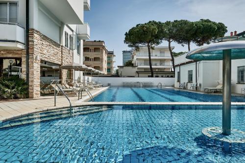 a swimming pool with chairs and umbrellas next to a building at Rouge Hotel International in Milano Marittima