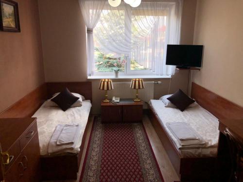 twee bedden in een kleine kamer met een raam bij U Bosmana in Brodnica