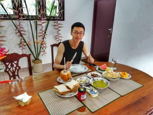 a man sitting at a table with a plate of food at Old Parkland Hostel in Galle