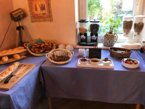 a table with a blue table cloth with bread and other foods at Hotel La Prairie in Méaudre