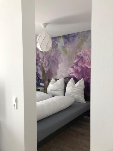 a bed with white pillows and a floral wall at Walnusshof Bad Salzungen in Bad Salzungen