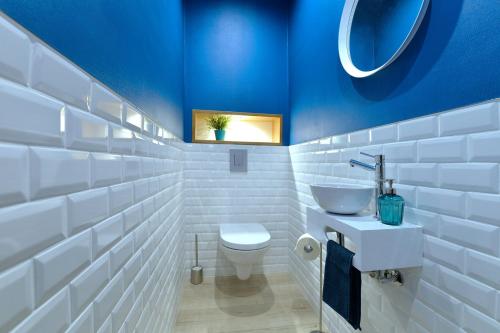 a bathroom with a white toilet and a blue wall at S'Harzala Bleu in Bergheim