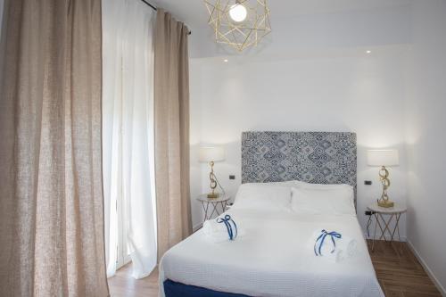 a bedroom with a white bed with blue and white sheets at AmaSi Affittacamere in Siracusa