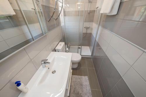 a white bathroom with a toilet and a sink at Vila Marija in Rab