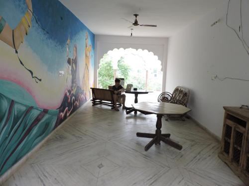 a man sitting at a table in a room with a mural at Radhika Palace Hotel in Pushkar