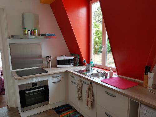d'une cuisine avec des murs rouges, un évier et une fenêtre. dans l'établissement Appartement 3 pièces, à Sedan