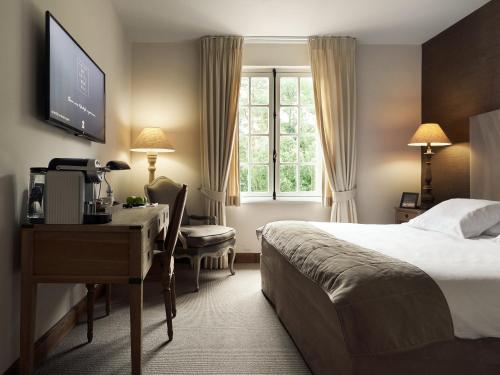 a hotel room with a bed and a desk and a computer at La Butte aux Bois a Small Luxury Hotel of the World in Lanaken