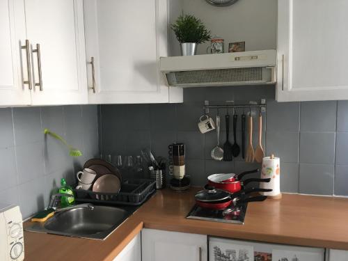 une cuisine avec des armoires blanches, un évier et une cuisinière dans l'établissement Montmartre Lovely, à Paris