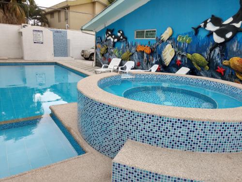 a swimming pool with a mural on the side of a building at Hotel Villa Turquesa in Tonsupa