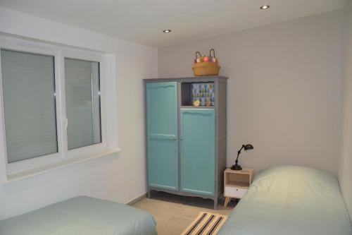 a bedroom with a blue cabinet and a window at Le Cottage in Harbonnières