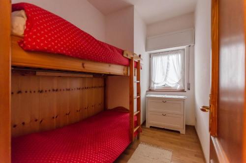 a bedroom with a bunk bed with a red bedspread at Continental 102 - 4 beds in San Vito di Cadore