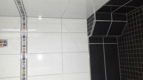 a shower with black and white tile on the wall at Ferienwohnung Karin Vogel in Hilchenbach