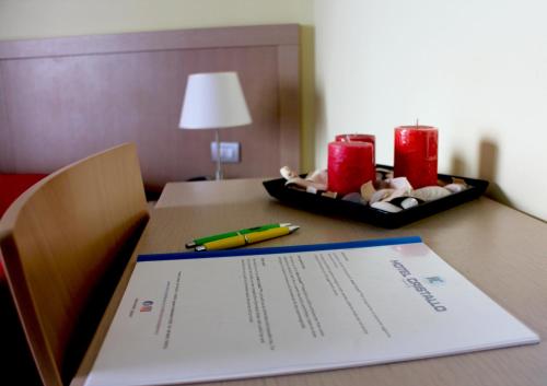 a desk with a paper and a pen and two candles at Hotel Cristallo in Lignano Sabbiadoro