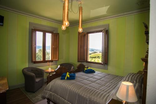 a bedroom with a bed and a chair and windows at Luce di Vino in Montalcino