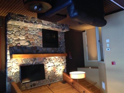 a living room with a stone fireplace with a television at C'mon Inn & Suites Fargo in Fargo