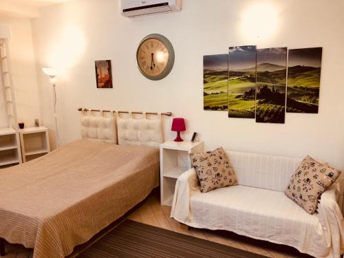 a bedroom with a bed and a clock on the wall at La Dolce Vita studio with free private parking in Siena