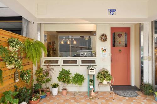 une façade de magasin avec des plantes en pot et une porte rouge dans l'établissement Good day, à Hualien