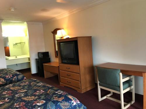 a hotel room with a bed and a desk and a television at Bayfront Inn Biloxi in Biloxi