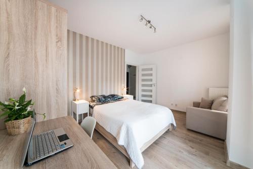 a bedroom with a bed and a desk with a laptop at Apartamenty City Tower od WroclawApartament-pl in Wrocław