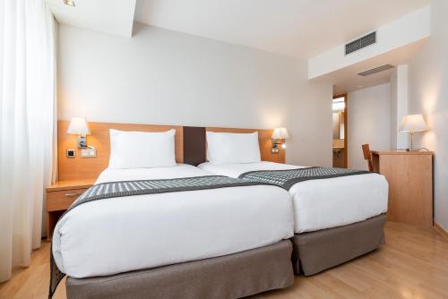 a bedroom with a large white bed with white pillows at Exe Puerta San Pedro in Lugo