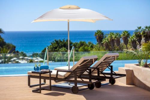 two chairs and a table with an umbrella on a patio at Gran Tacande Wellness & Relax Costa Adeje in Adeje