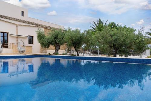 een zwembad met bomen en een gebouw bij Momentum Wellness Bioresort in Marinella di Selinunte