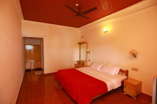 a bedroom with a bed and a ceiling fan at Kerala House in Thekkady