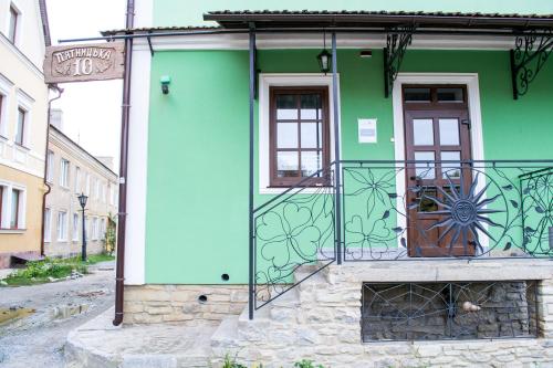 a green building with a door on a street at Home Hotel in Kamianets-Podilskyi