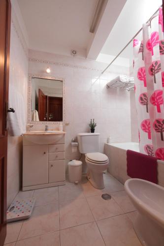 a bathroom with a toilet and a tub and a sink at Casa das Andorinhas in Faro
