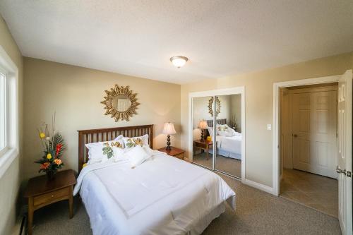 1 dormitorio con 1 cama blanca grande y espejo en McKinnon Pointe #302, en Edmonton