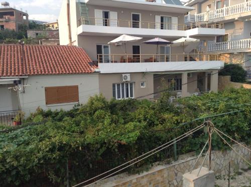 a white house with a balcony with an umbrella at Vila Rapo in Himare