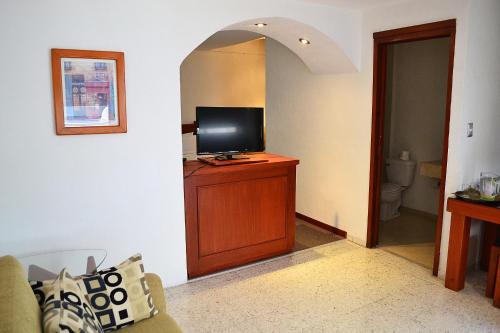 a living room with a television on a wooden cabinet at Hotel Campestre Inn in León