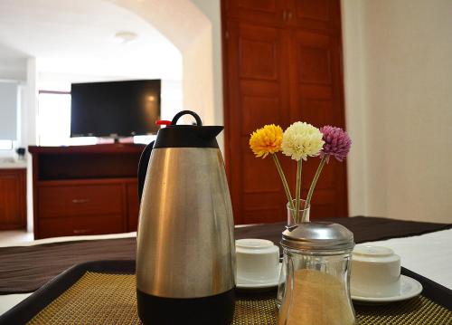 a tea kettle and vase of flowers on a table at Hotel Campestre Inn in León
