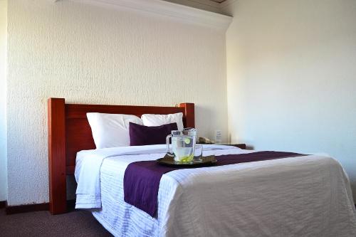 a hotel room with a bed with a glass on a tray at Hotel Campestre Inn in León